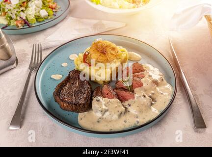 Schweinesteak mit Kartoffelgratin und cremiger Sauce serviert Der Restauranttisch Stockfoto