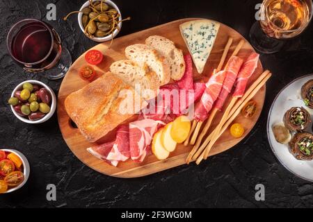 Italienisches Essen. Verschiedene Antipasti, aufgenommen von oben auf schwarzem Hintergrund Stockfoto