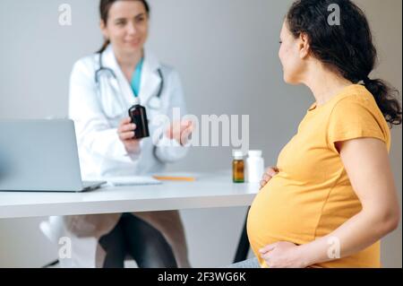 Gesundheitsversorgung von schwangeren erwachsenen Frau. Mixed Race schwangere Frau in sitzt bei Arzttermin, Beratung und Behandlung erhalten, entkokelt weibliche Arzt an einem Tisch sitzen Beratung geben Stockfoto