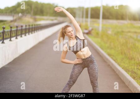 Junge schöne Frau ist in Stretching im Freien in einer Stadtstraße engagiert. Stockfoto
