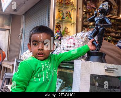 Ein Kind hält krishna Idol in den Straßen von mathura mit selektivem Fokus auf Thema und fügte Lärm und Körner. Stockfoto