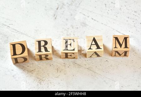 Fünf Holzwürfel mit BUCHSTABENTRAUM (Akronym für Engagement Responsibility Education Attitude Motivation) auf weißem Stein wie Brett, Blick von oben Stockfoto