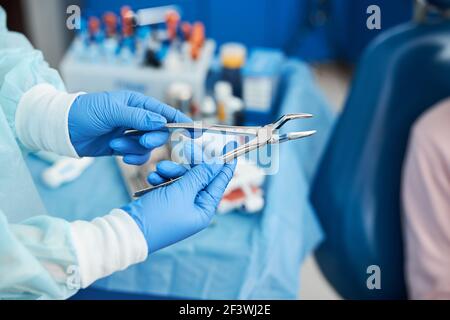 Extraktion von Pinzetten in den Armen der Zahnmediziner Stockfoto