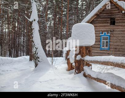 Große Schneekappen auf den Stumps des Zauns im Winter. Ein Holzzaun schützt das Gebiet des Hauses. Stockfoto