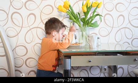 Das Kind isst alleine am Tisch. Hochwertige Fotos Stockfoto