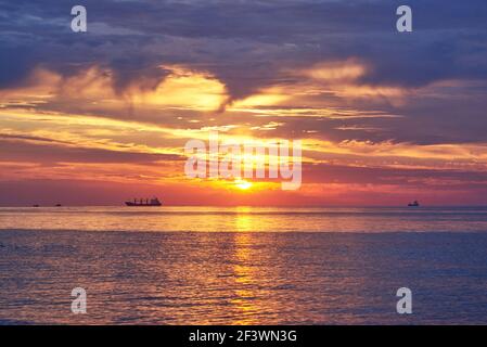 Sonnenuntergang am wolkenlosen Himmel auf dem Meer, Schiffe stehen am Horizont. Stockfoto