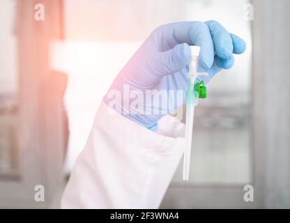 Der Arzt hält vor dem Hintergrund des Labors einen intravenösen Katheter in der Hand. Bluttransfusionskonzept und Blutdiagnostik Stockfoto