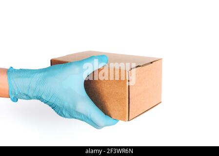 Hand in medizinischen Handschuh gibt Handwerk Box auf blauem Hintergrund. Kontaktlose Lieferung, Online-Shopping-Konzept. Banner, Kopierbereich. Sichere Verpackung während Stockfoto