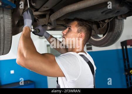 Junge Werkstatt unter dem Auto in einer Werkstatt Stockfoto