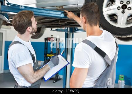 Kfz-Werkstatt-Mechaniker, die Schäden an einem Auto untersuchen Stockfoto