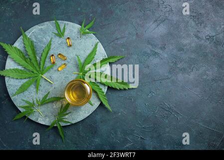 Glasflasche mit pflanzlichem cbd-Öl, Kapseln und Hanfblatt auf dunklem Hintergrund. Flach liegend, Kopierplatz. Draufsicht. Banner. Alternative Medizin. Unverzichtbar Stockfoto