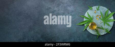 Glasflasche mit pflanzlichem cbd-Öl, Kapseln und Hanfblatt auf dunklem Hintergrund. Flach liegend, Kopierplatz. Draufsicht. Banner. Alternative Medizin. Unverzichtbar Stockfoto