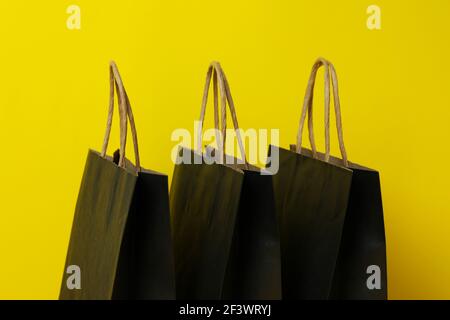 Leere schwarze Papiertüten auf gelbem Hintergrund Stockfoto