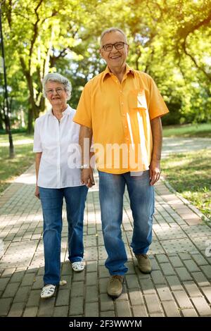 Reizendes Seniorenpaar, das zusammen durch den Park läuft Stockfoto