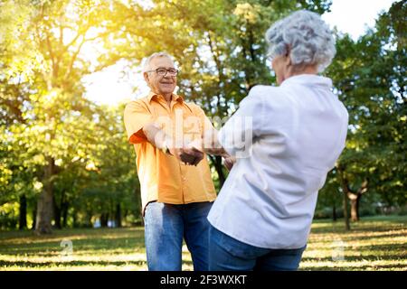 Ältere Paare, die Spaß haben und tanzen im Park, genießen Sie gemeinsam im Freien Stockfoto