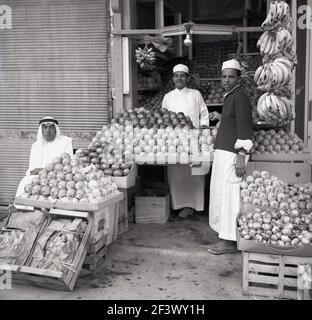 1960s, historische, arabische Handwerker in traditioneller Kleidung auf ihrem Obststand, Jeddah, Saudi-Arabien. Stockfoto