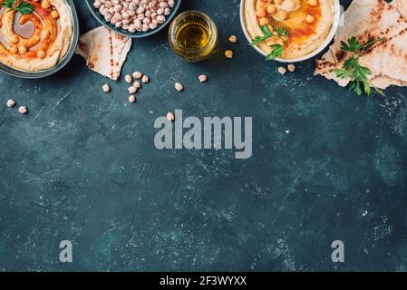 Kichererbsen Hummus, Olivenöl, rohe Kichererbsen, geräucherter Paprika, Pita auf dunklem Hintergrund. Nahöstliche, jüdische Küche oder arabische Gerichte. Draufsicht. Kopieren Stockfoto