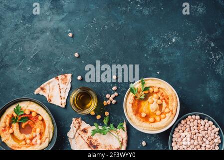 Kichererbsen Hummus, Olivenöl, rohe Kichererbsen, geräucherter Paprika, Pita auf dunklem Hintergrund. Nahöstliche, jüdische Küche oder arabische Gerichte. Draufsicht. Kopieren Stockfoto