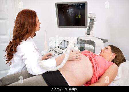 Schwangere Frau, die Ultraschallbehandlung im Krankenhauszimmer erhält Stockfoto