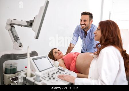 Glückliches Paar, das Ultraschallergebnisse mit dem Arzt im Krankenhaus betrachtet Zimmer Stockfoto