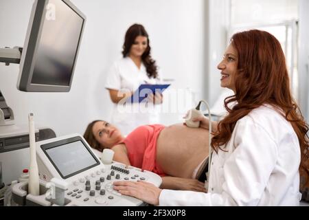 Schwangere Frau, die Ultraschallbehandlung im Krankenhauszimmer erhält Stockfoto