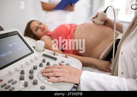 Schwangere Frau, die Ultraschallbehandlung im Krankenhauszimmer erhält Stockfoto