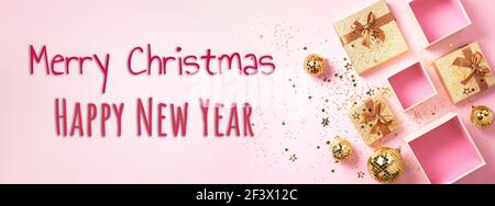 Geschenkschachtel, goldglänzende Discokugeln, glitzernder Goldglitter auf rosa Hintergrund. Weihnachtskugeln, Sterne funkeln. Neujahr, Weihnachten, Valentinstag Stockfoto