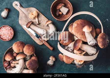Frische Waldpilze auf dunklem Hintergrund. Draufsicht. Speicherplatz kopieren. Herbsterntekonzept. Frisch gepflückte Steinpilze im Korb Stockfoto