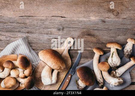 Frische Waldpilze auf Holzhintergrund. Draufsicht. Speicherplatz kopieren. Herbsterntekonzept. Frisch gepflückte Steinpilze im Korb Stockfoto