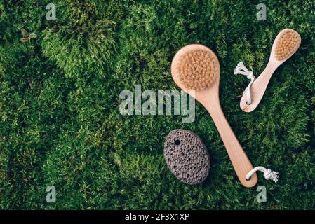Set aus Bambus-Massagebürsten auf grünem Moos-Hintergrund. Draufsicht. Speicherplatz kopieren. Naturbürste, Öko-Kosmetik und Werkzeuge. Kein Abfall, Kunststoff-frei Stockfoto