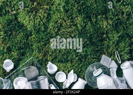 Lebensmittel-Plastikverpackung, Müll auf grünem Moos Hintergrund nach dem Picknick im Wald. Draufsicht. Speicherplatz kopieren. Recycling von Kunststoff. Umweltverschmutzung Stockfoto