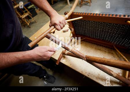 Villemer (Pariser Gegend), September 2020 : Werkstatt des Maison Gatti, Rattan-Möbelhersteller. Nahaufnahme der Hände des Arbeiters. Rattan und wicke im Freien Stockfoto