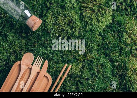 Glasflasche, umweltfreundliches Bambusbesteck, Verpackungen, Behälter zum Mitnehmen für Picknick oder Mittagessen auf grünem Mooshintergrund. Draufsicht. Speicherplatz kopieren Stockfoto