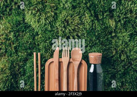 Nachhaltiger Lebensstil. Kein Abfall, frei von Kunststoff. Glasflasche, Holzbesteck, Bambus-Lebensmittelbehälter auf grünem Mooshintergrund. Draufsicht. Speicherplatz kopieren Stockfoto