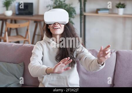 Frau zu Hause trägt Virtual-Reality-Headset spielen Spiel auf Das Sofa Stockfoto