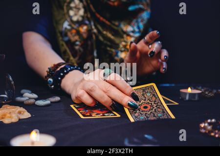 Eine Zauberin legt Wahrsagerkarten Tarot auf den Tisch. Nahaufnahme der Hände. Das Konzept der Kartenlesung, Magie und Esoterik. Stockfoto