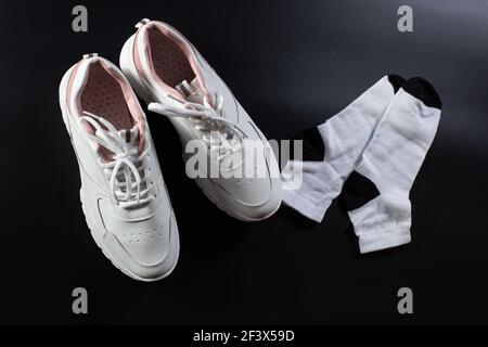 Whiet orthopädische Sneakers mit Socken auf schwarzem Hintergrund, Ansicht von oben. Stockfoto