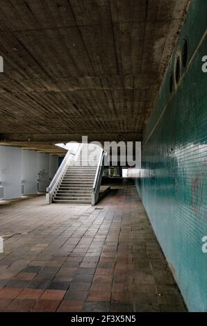 Alte städtische U-Bahn mit leerer Treppe, Betondecke, abgenutzte braune Fliesen auf dem Boden und grünes Mosaik an der Wand Stockfoto