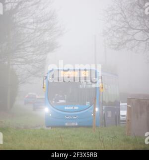 Stourbridge, Großbritannien. März 2021, 18th. Wetter in Großbritannien: Am frühen Morgen ist der Nebel in Teilen der West Midlands langsam zu heben. Ein frühmorgendlicher Bus mit Scheinwerfern bringt die wenigen Fahrgäste auf den Weg zur Arbeit. Kredit: Lee Hudson/Alamy Live Nachrichten Stockfoto