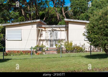 Ein nach dem Krieg modernes Fibro-Haus mit einem geteilten Schmetterlingsdach im Südküstendorf Bendelong, New South Wales, Australien Stockfoto