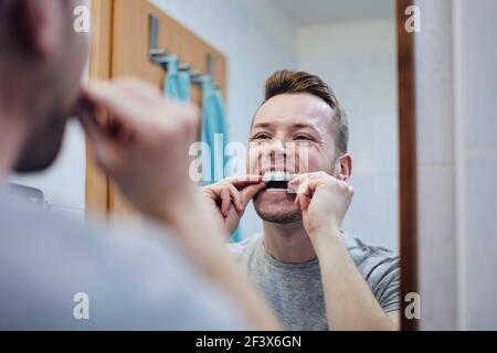 Junger Mann bereitet Silikon-Tablett für Zahnaufhellung mit Bleichgel. Themen Zahngesundheit, Pflege und Schönheit. Stockfoto