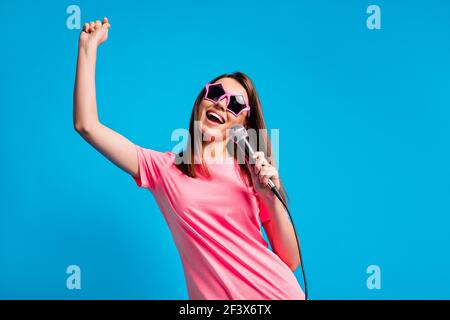 Low-Winkel-Ansicht Foto von positiven glücklich Mädchen singen Mikrofon Tragen von Sonnenschutzglas isoliert auf hellblauem Hintergrund Stockfoto