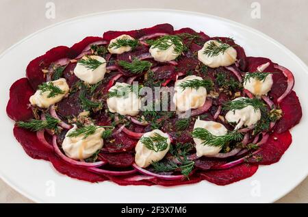 Nahaufnahme von Rote Beete Salat serviert auf weißem Teller mit roten Zwiebeln, Dilll und Joghurt mit Tahini Stockfoto
