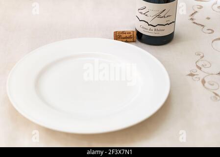 Weißer leerer Teller mit Flasche Cote du Rhone Roche Audran Französischer Rotwein und Weinkorken Stockfoto