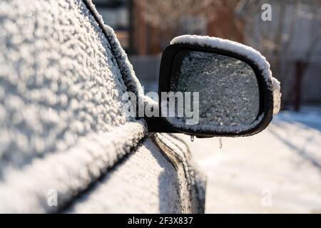 Auto mit Eis und Eiszapfen nach Glatteisregen bedeckt. Eisbedecktes Autofenster aus der Nähe. Schlechtes Winterwetter, EissturmWinter frostige Szenen. Stockfoto