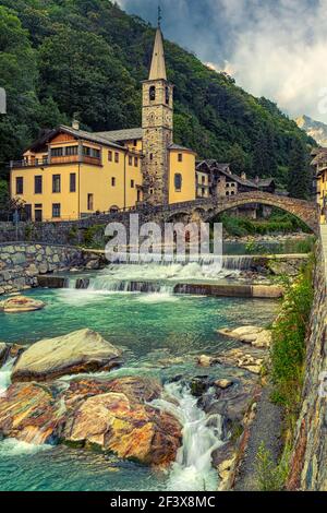 Das alpine Dorf Fontainemore im Lys-Tal mit seiner römischen Brücke, die den Alpenstrom der Lys überquert. Aosta, Aostatal, Italien Stockfoto