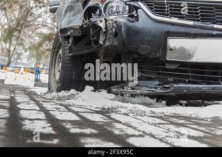 Crash ein gebrochenes Auto im Winter auf der Straße unter dem Schnee. Nahaufnahme, Detail Stockfoto