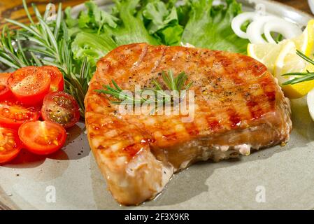 Thunfischsteak auf dem elektrischen Grill gekocht. Thunfisch serviert auf einem Teller mit frischen Kräutern und Gemüse. Gesunde nahrhafte, gesunde Ernährung für eine gesunde Stockfoto