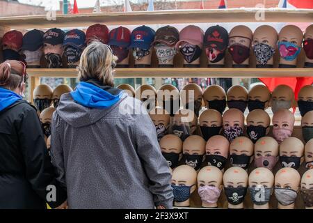 Die Menschen schauen sich eine Ausstellung von Schaufensterpuppen Köpfe tragen Gesichtsmasken zum Verkauf in Toronto chinatown Nachbarschaft während COVID-19 Pandemie. Stockfoto