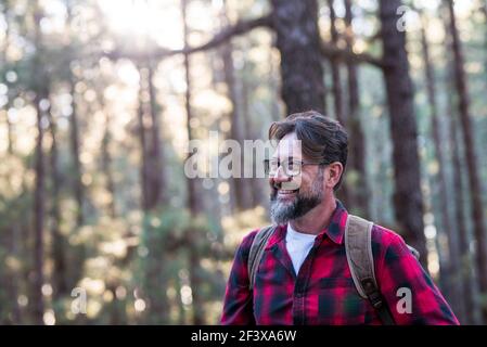 Nahaufnahme eines selbstbewussten bärtigen Mannes in einem Outdoor-Park. Profil jung schön lächelnd bärtiger Mann Junge Erwachsene Hipster Wandern Wald - glücklich peo Stockfoto